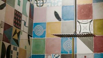 Un baño con azulejos geométricos de colores en las paredes y un toallero de metal.
