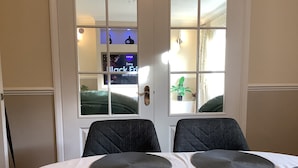 Un coin repas avec une table dressée pour deux personnes, une bougie rose et une vue sur une pièce où l’on peut voir à la télévision la publicité de « Curry’s Every Black Friday ».