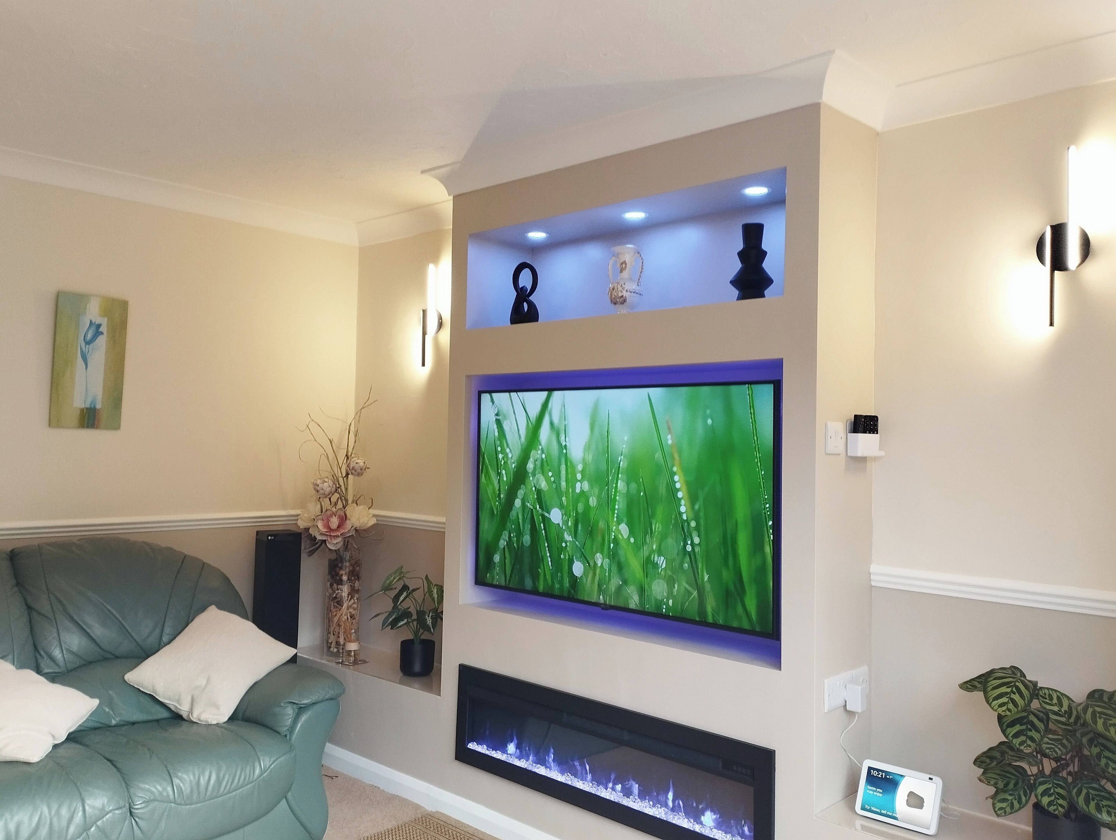 Un salon avec un canapé de couleur turquoise, un téléviseur à écran plat, une cheminée et des objets décoratifs accrochés au mur.