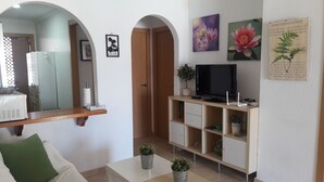 Un soggiorno con televisore, scaffali, uno specchio e una porta.