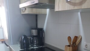 Una cucina con mobili in legno, un piano cottura a induzione nero, una macchina da caffè e un lavandino in acciaio inossidabile.