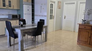 A compact kitchen with a dining area, featuring a refrigerator, microwave, and a dining table with chairs.