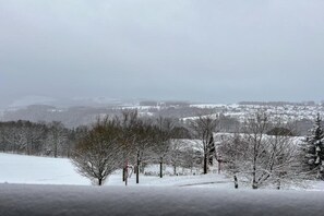 A snowy landscape with bare trees and a distant view of a town. - Slopeside Stay in Méribel (Les allues)