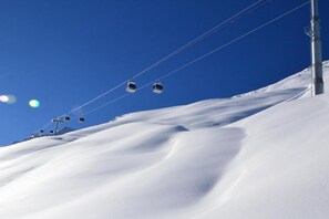 A ski lift with chairs ascending a snowy slope. - Slopeside Stay in Méribel (Les allues)