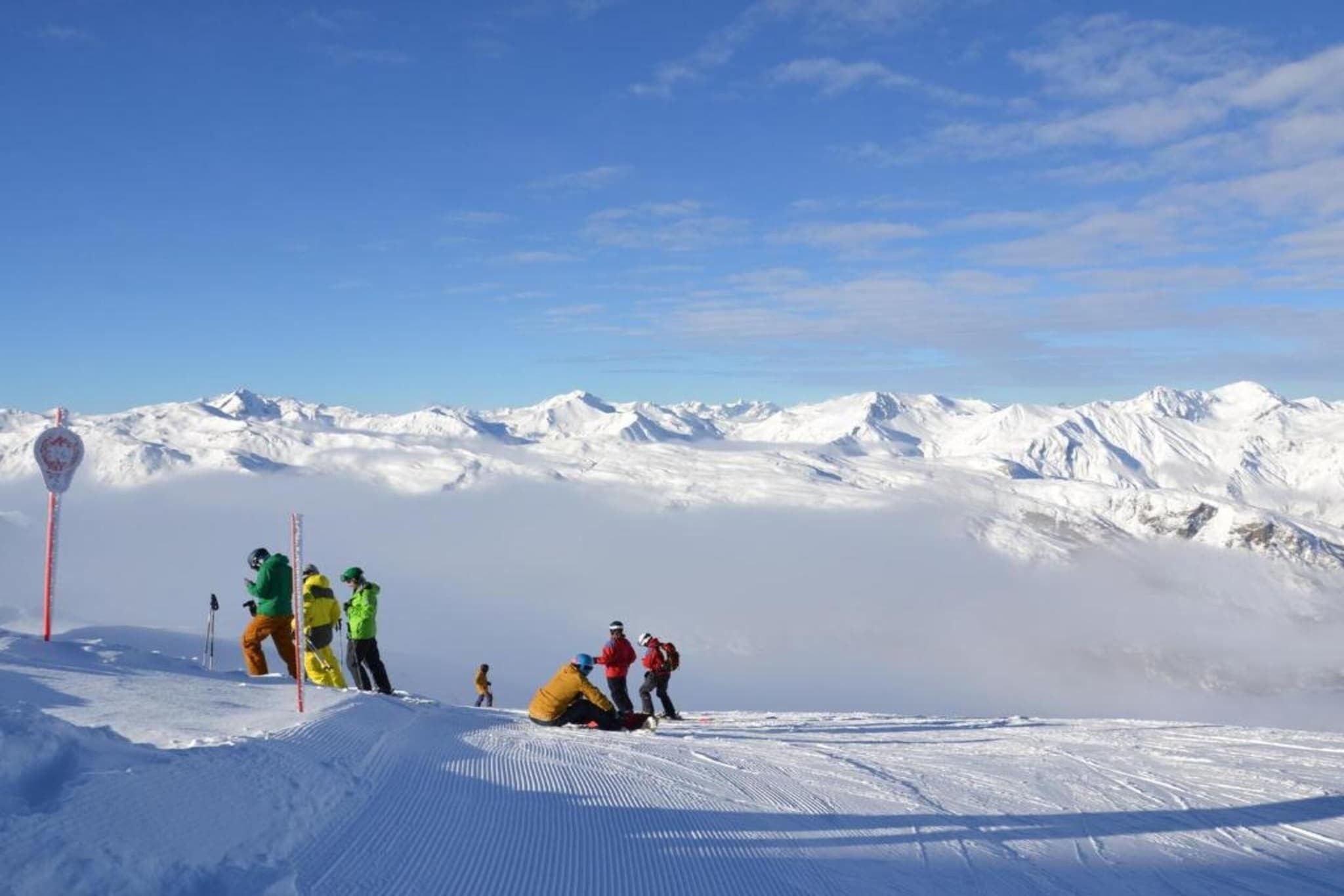 A snowy mountain landscape with skiers and a red pole.