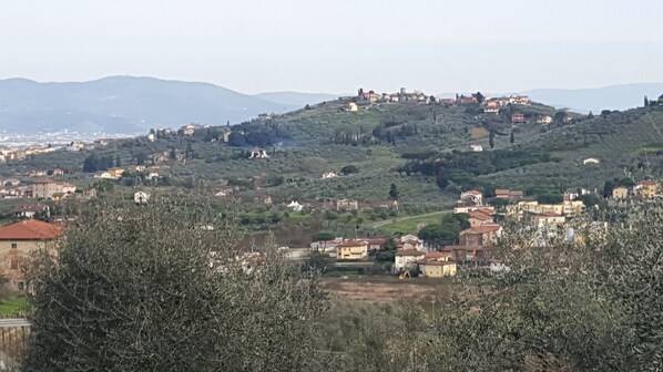 A hilly landscape with scattered buildings, including a prominent structure on a hilltop. - Casa Leonardo in the Tuscan countryside near Florence Prato and Pistoia (Quarrata PT)