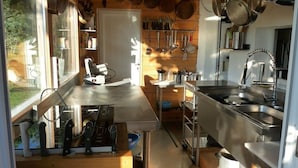 A compact kitchen with a stainless steel countertop, hanging utensils, and a window providing natural light.