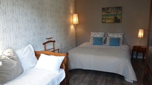 Una habitación con dos camas, una silla y dos lámparas de noche.