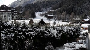 Un pueblo cubierto de nieve con edificios y árboles, visto desde una ventana.