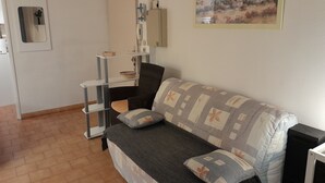 Un salon avec un canapé, une petite table d’appoint, un miroir et un tableau accroché au mur.