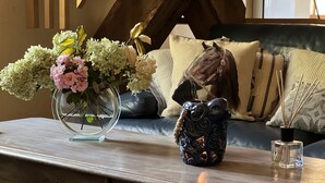 A wooden coffee table with a vase of flowers, a decorative owl figurine, and a candle holder. - Le Lapin sur le Toit - Beautifully restored 18th-century barn, private heated swimming pool (Rouffignac-Saint-Cernin-De-Reilhac)