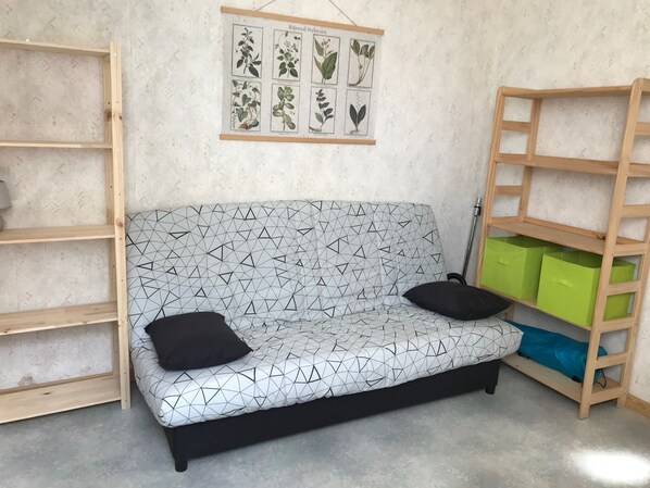 Una habitación con un sofá de estampado geométrico, un herbario botánico y estanterías.