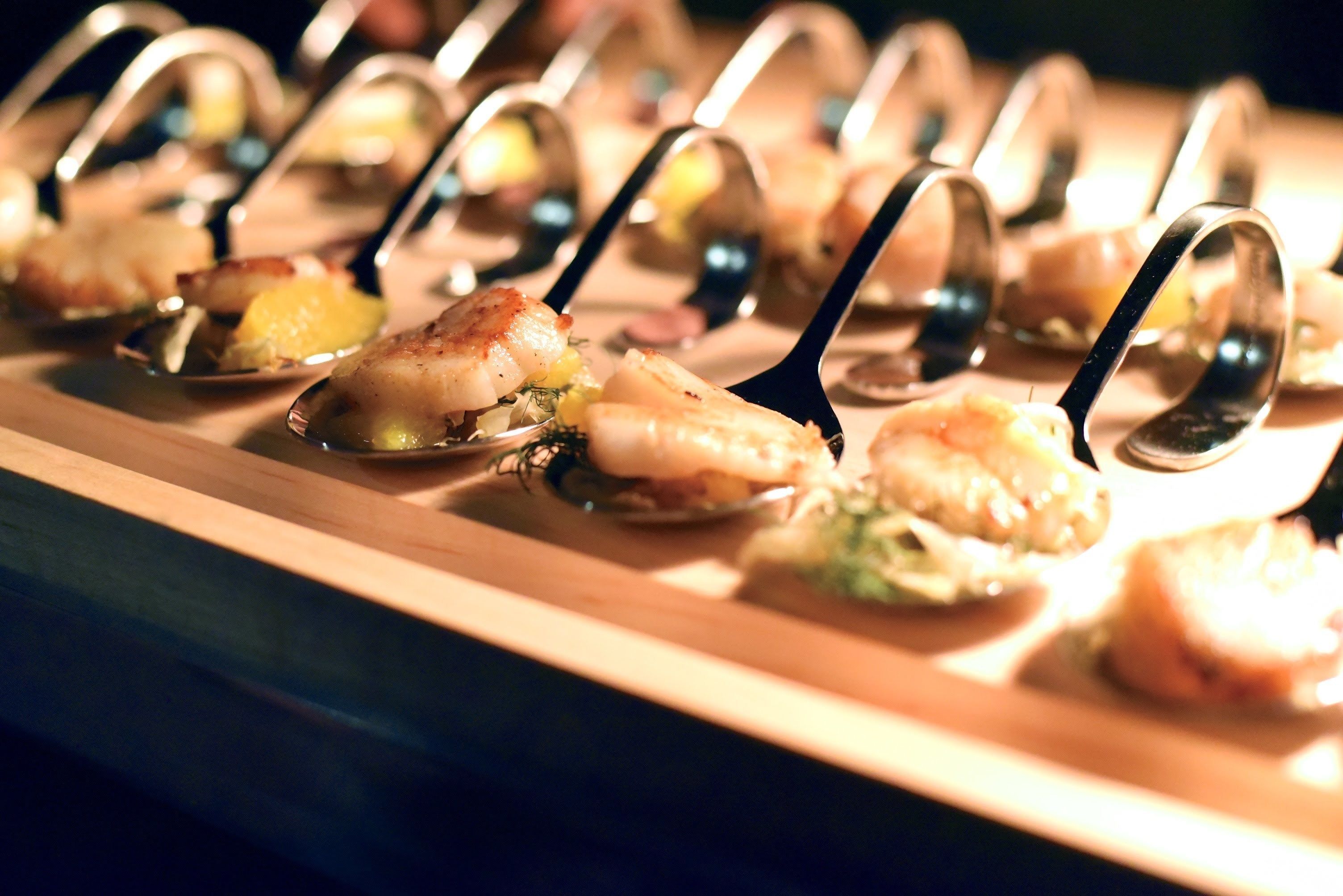 A row of seafood appetizers on a wooden serving board.