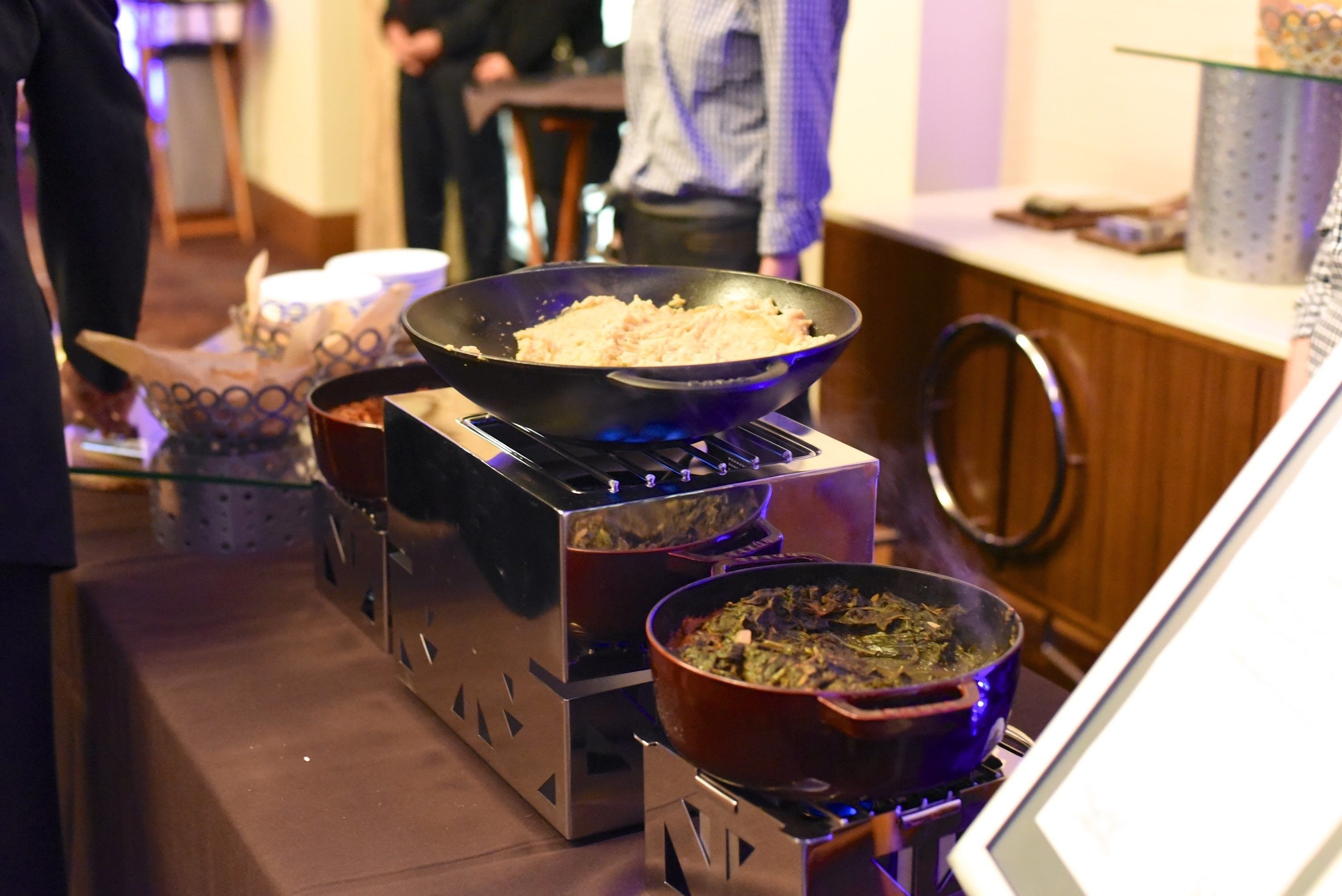 A kitchen with a stove, a frying pan, and a pot on a portable gas burner.