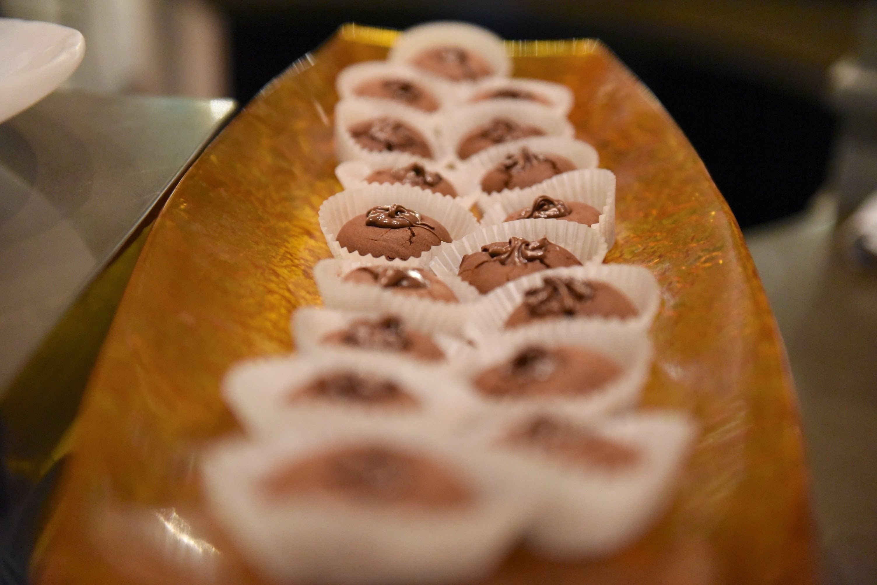 Una bandeja de pequeños pasteles cubiertos de chocolate en vasos de papel.