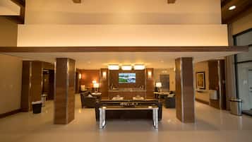 Um lobby moderno com mesa de bilhar, assentos confortáveis e uma televisão na parede.