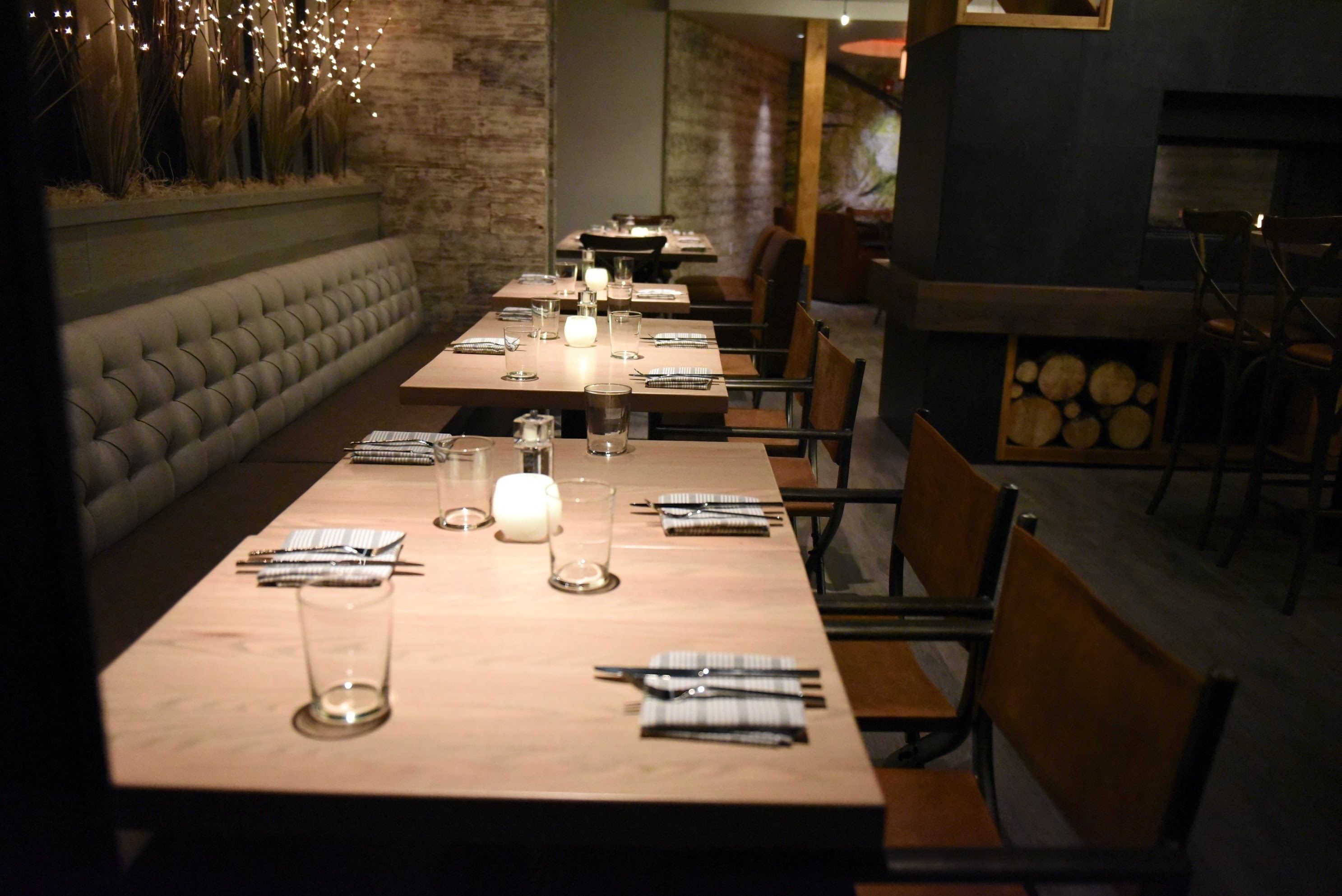 En restaurant med lange træborde dækket til spisning, med stearinlys og bestik.