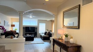A spacious living room with a large TV, comfortable seating, and a decorative mirror. - Close strip 3 bedroom Home (Las Vegas,)