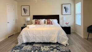 A bedroom with a bed, a ceiling fan, a nightstand, a lamp, and a window. - Close strip 3 bedroom Home (Las Vegas,)