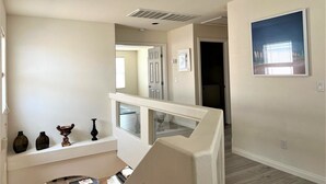 A hallway with a staircase, a framed picture on the wall, and a door leading to another room. - Close strip 3 bedroom Home (Las Vegas,)