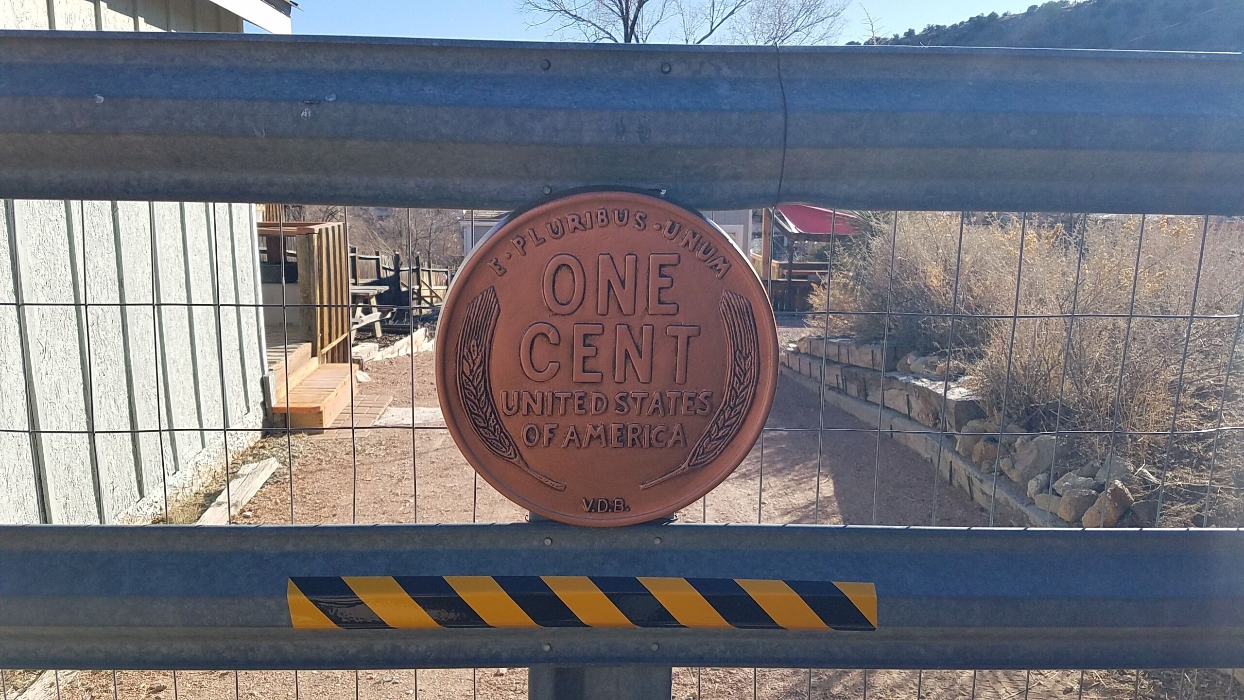 Una reja de metal con una placa circular que dice 'ONE CENT UNITED STATES OF AMERICA' y 'V.D.B.'