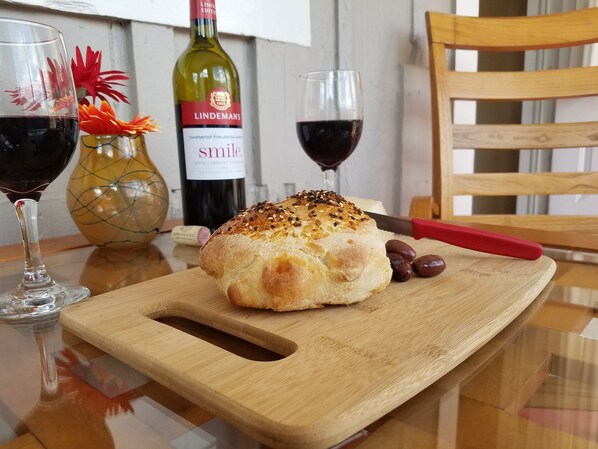 Ett bröd på en träskärbräda, en kniv och två glas rött vin på ett bord.