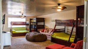 A bedroom with bunk beds, a bean bag, a small couch, and a bookshelf.