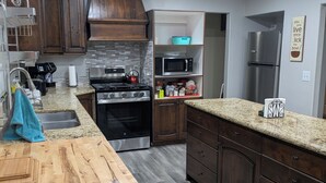 A modern kitchen with dark wooden cabinets, stainless steel appliances, and a wooden island.