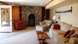 Ein gemütliches Wohnzimmer mit Kamin aus Stein, Ledersofas und einem Couchtisch mit Büchern.