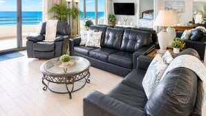 Un salon moderne avec un grand canapé, des fauteuils, une table basse et un téléviseur.