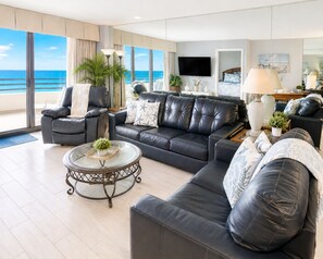A modern living room with a large sofa, armchairs, a coffee table, and a TV.