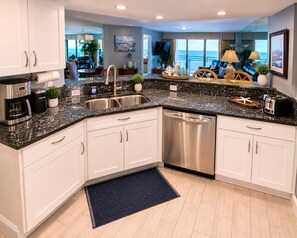 A modern kitchen with a dishwasher, double sink, and a coffee maker.