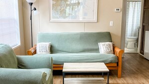 A living room with a green sofa, a wooden coffee table, and a lamp.