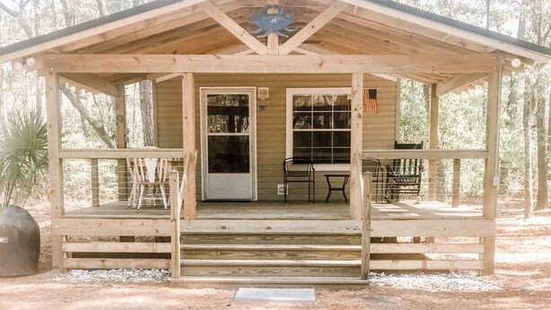A wooden cabin with a porch, a door, and a window.