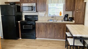 A compact kitchen with a refrigerator, microwave, stove, and sink.