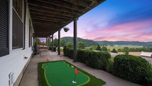 A covered porch with a miniature golf course, a view of the countryside, and a wooden structure with columns. - Big Pine Alpine | Pickleball, GameRoom, HotTub, EpicViews, Gym & More (Laurelville)