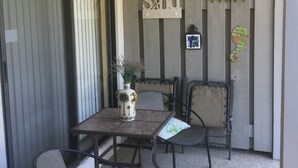 Eine Terrasse mit Tisch, Stühlen, einem dekorativen Schild und einer kleinen Pflanze.