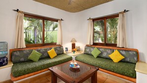 A room with two green sofas with patterned cushions, a wooden coffee table, and a water dispenser on the left. - Villas del Rio: 1BR/1BA with dipping pool 1 block from the beach. (Sayulita)