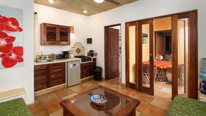 A compact kitchen with wooden cabinets, a sink, and a coffee machine. There is a glass table with a decorative plate in the center. - Villas del Rio: 1BR/1BA with dipping pool 1 block from the beach. (Sayulita)