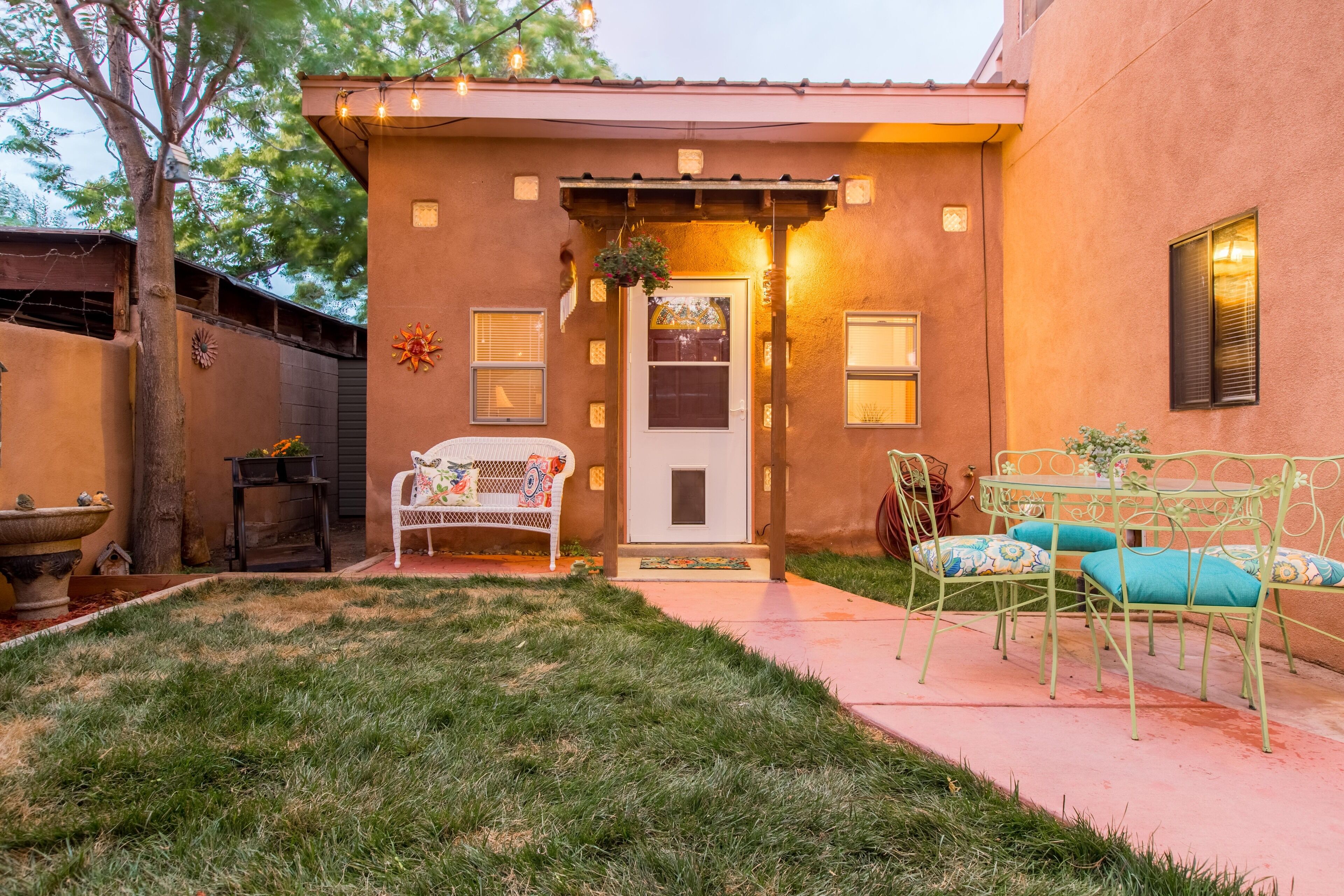 Una casa con porche delantero, un pequeño jardín y mobiliario exterior.