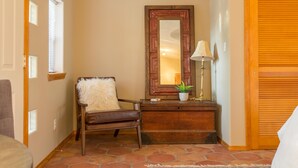 Une pièce comprenant un banc en bois, un miroir, une lampe et une petite plante posée sur une commode en bois.