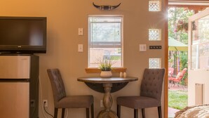 Un espace de vie compact comprenant un téléviseur, un réfrigérateur et un petit coin repas avec deux chaises et une table.