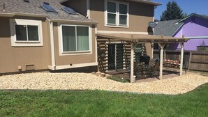 A house with a patio area, a covered seating area, and a gravel driveway. - Charming home in Mountain Shadows. (Colorado Springs)