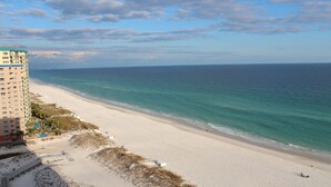 Une plage avec un grand hôtel, un ciel dégagé et une mer calme.