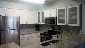 Una cocina moderna con electrodomésticos de acero inoxidable, armarios blancos y un salpicadero con diseño en espiga.