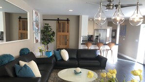Ein modernes Wohnzimmer mit einem schwarzen Ecksofa, einem runden Couchtisch und einer Zimmerpflanze.