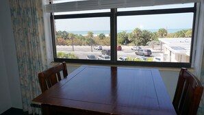 A room with a large window overlooking a parking lot and a beach. - Gulf views! 2 Bedroom vintage condo - Third/Top Floor. FN #205 (St Pete Beach)
