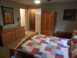 Un dormitorio con una cama de madera, un aparador, un armario y un espejo en la pared.