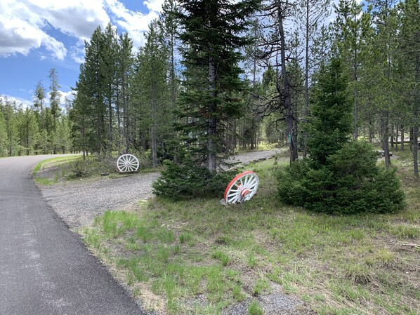 A gravel path curving through a forest with two large white and red wheels.