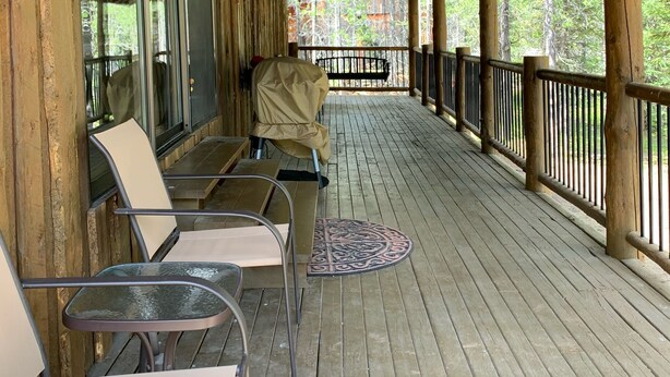 A covered outdoor seating area with wooden flooring and metal chairs.